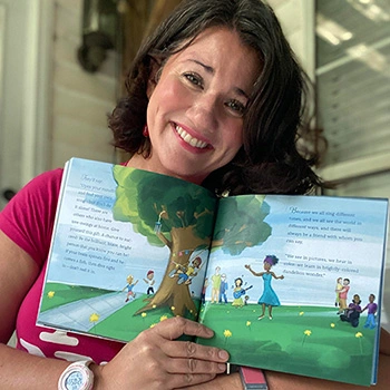 Alison Trotter, the author, holding Tree Swing Called Belonging open to an inside spread.